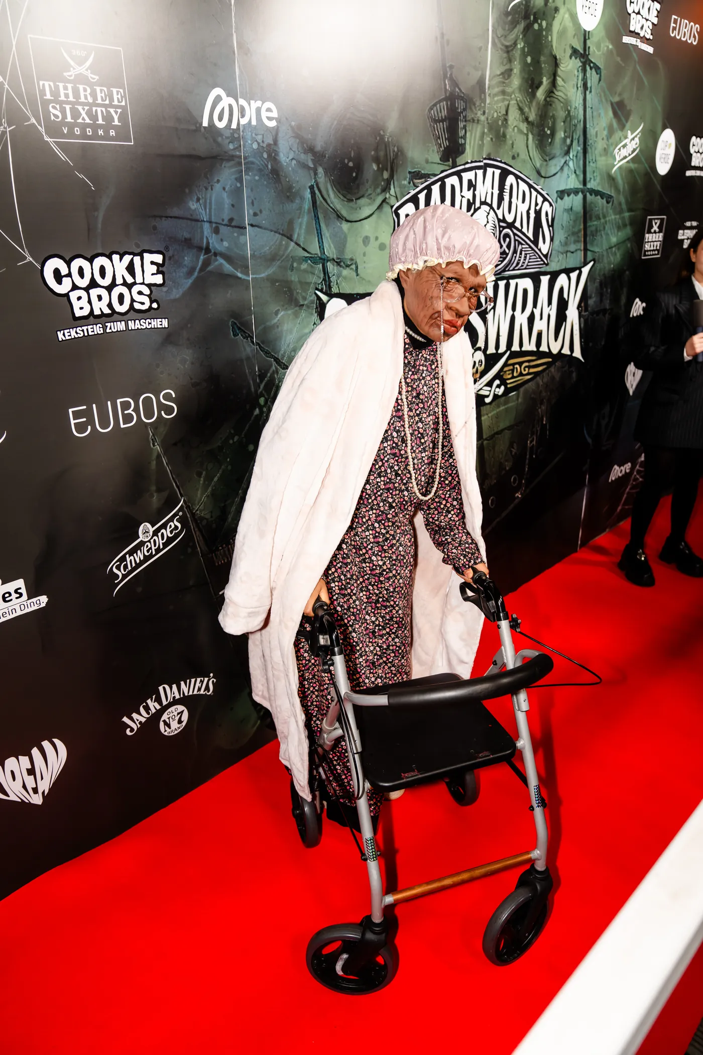 Paar in Comic-Kostümen mit Frettchen auf dem Red Carpet
